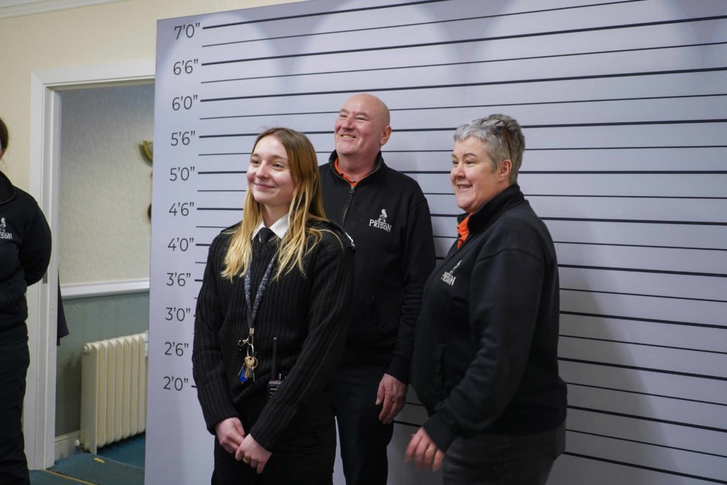 Three Cove Group team members posing in front of a height chart backdrop.